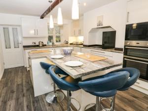 a kitchen with a table and blue bar stools at Woods Lane Cottage in Oldham