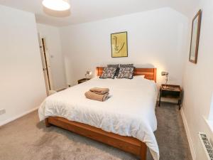 a bedroom with a large bed with white sheets at Woods Lane Cottage in Oldham