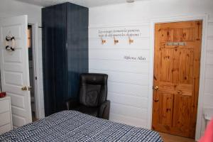 ein Schlafzimmer mit einem Bett und einem schwarzen Stuhl in der Unterkunft Corail de mer 4 à 2 min de la plage in Sainte-Luce-sur-Mer