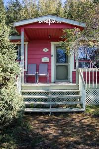 una casa roja con 2 sillas en el porche en Corail de mer 4 à 2 min de la plage, en Sainte-Luce-sur-Mer