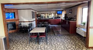 a restaurant with a table and chairs and a kitchen at Baymont by Wyndham Battle Creek/I-94 in Battle Creek