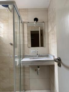 La salle de bains est pourvue d'un lavabo et d'une douche. dans l'établissement Pousada Guarujá, à Guarujá