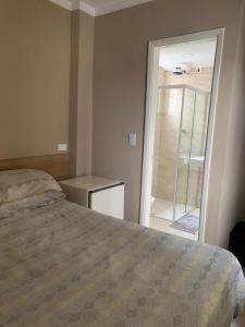 a bedroom with a bed and a door to a bathroom at Pousada Guarujá in Guarujá