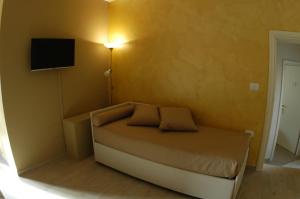 1 dormitorio pequeño con 1 cama y TV en la pared en Dimora Offidius, en LʼAquila