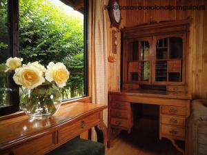 a vase of flowers on a table next to a window at Cabaña Familiar Panguipulli in Panguipulli