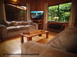 Sala de estar con 2 sofás y mesa de centro en Cabaña Familiar Panguipulli, en Panguipulli