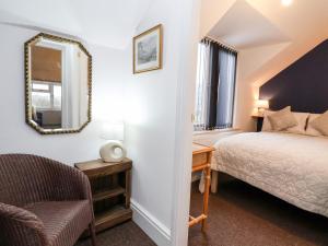 a bedroom with a bed and a mirror and a chair at Smithy Cottage in Wrexham