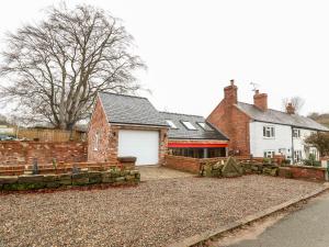 a house with a white garage and a brick building at Smithy Cottage in Wrexham