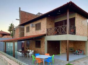 a building with a table and chairs in front of it at Paraíso Pé na Areia em Maragogi in Maragogi