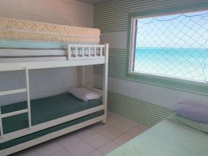a room with two bunk beds and a window at Paraíso Pé na Areia em Maragogi in Maragogi
