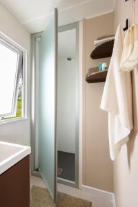 a bathroom with a shower with a sink and a mirror at Camping Marina Plage in Vitrolles