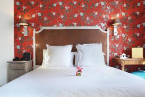 un osito de peluche sentado en una cama en un dormitorio en Le Robinet d'Or, en París