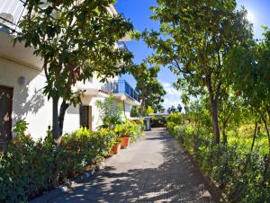 einen Gehweg vor einem weißen Gebäude mit Bäumen in der Unterkunft Villa Santantonio in Giardini-Naxos