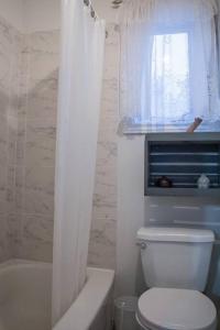 La salle de bains est pourvue de toilettes, d'une fenêtre et d'une baignoire. dans l'établissement Chalet Le Marin à 5 minutes du centre ville, à Sainte-Flavie