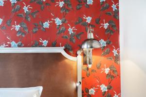 パリにあるLe Robinet d'Orの花の壁紙を用いた赤い壁のベッドルーム1室