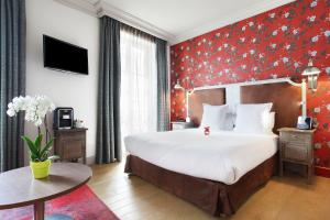 - une chambre avec un grand lit et un mur rouge dans l'établissement Le Robinet d'Or, à Paris