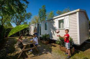 een jongen die met een bal speelt voor een caravan bij Camping Marina Plage in Vitrolles