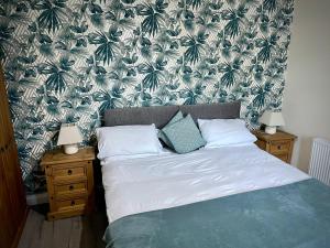 une chambre avec un lit avec un papier peint vert et blanc dans l'établissement Milburn Cottage 2- Luxury Accommodation, à Monkwearmouth