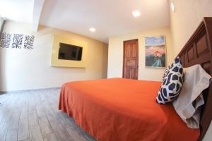 a bedroom with a bed and a tv on the wall at Hotel Camino de Piedra in Guanajuato
