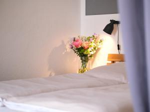 un jarrón de flores sentado encima de una cama en Smile, wunderschöne Wohnung direkt am Strand, en Harrislee