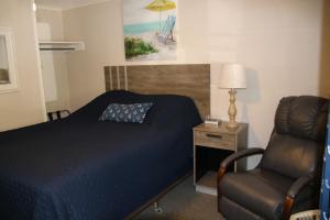 a bedroom with a bed and a chair and a lamp at West Winds Motel & Cottages in Clayton