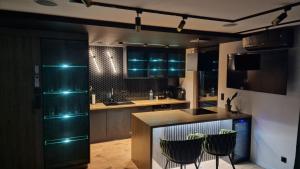- une cuisine avec un comptoir et 2 chaises dans l'établissement Apartament Czarna Perła z dużym tarasem NA Dachu 75m2 , PROJEKTOR ,garaż podziemny, à Kielce