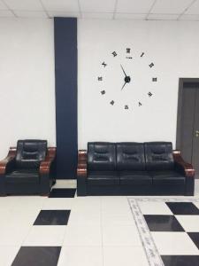 two black leather couches and a clock on a wall at Andalusia Hotel in Nouakchott