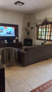 uma sala de estar com um sofá e uma televisão de ecrã plano em Linda chacara em Itatiba