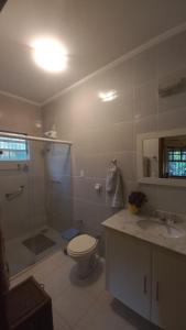 uma casa de banho com um WC, um chuveiro e um lavatório. em Linda chacara em Itatiba