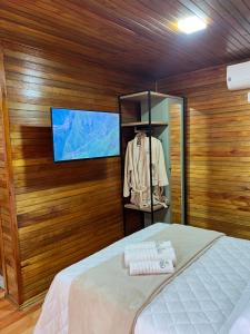 1 dormitorio con 1 cama y TV en la pared en Recanto da Maju, en Bom Jardim da Serra