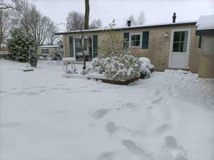 een tuin bedekt met sneeuw voor een huis bij chalet Klein Vechtdal in Ommen