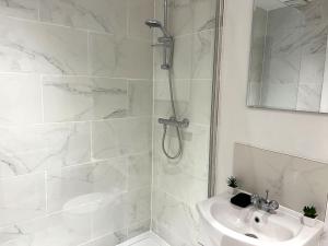 uma casa de banho branca com um chuveiro e um lavatório. em New Two Bedroom Premium Apartment - Skylight - Northampton Town Centre em Northampton