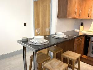 uma cozinha com uma mesa com cadeiras e copos de vinho em New Two Bedroom Premium Apartment - Skylight - Northampton Town Centre em Northampton