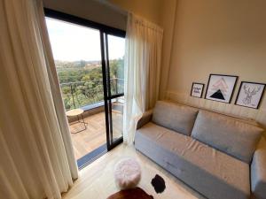 a living room with a couch and a large window at Carpe Diem Hotel Duplex in Campos do Jordão