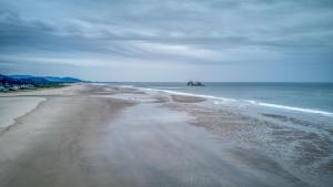vistas a una playa con un barco en el agua en The Sand Castle - Meredith Lodging, en Rockaway Beach