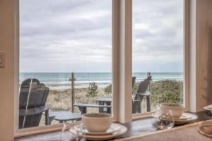 Una mesa de comedor con vista a la playa desde una ventana. en The Sand Castle - Meredith Lodging, en Rockaway Beach