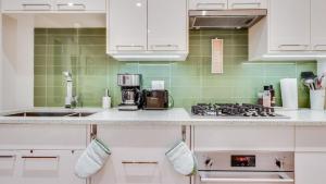 una cocina con armarios blancos y azulejos verdes en City Side Near Cook Street Village, en Victoria
