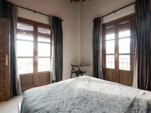 1 dormitorio con 1 cama y 2 ventanas grandes en Loft wifi Centro espectacular terraza con todos los servicios, en Granada