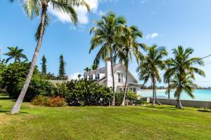 a house on the beach with palm trees at Folly & Guest House home in Governorʼs Harbour