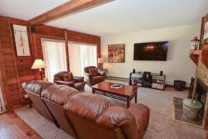 a living room with a leather couch and a tv at Anaconda 101 in Copper Mountain