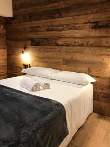 a bedroom with wooden walls and a bed with white pillows at 4Seasons appartamenti in Sauze dʼOulx