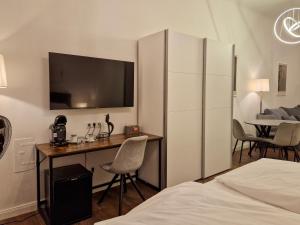 ein Hotelzimmer mit einem Schreibtisch und einem TV an der Wand in der Unterkunft Pension Mozart - Newly Renovated 2021 in Wien
