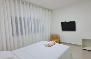 a white room with a bed and a tv at Apartamento no centro próximo a JK. in Palmas