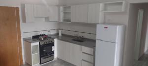 a small kitchen with white cabinets and a white refrigerator at DEPARTAMENTO VILLA CARLOS PAZ CENTRO in Villa Carlos Paz