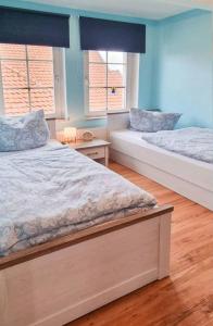 2 camas en una habitación con paredes y ventanas azules en Weiße Villa Whg. 2, en Duderstadt