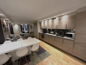 uma grande cozinha com um balcão branco e cadeiras em Stetind - Modern apartment with free parking em Narvik