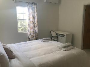 a white bed in a room with a chair and a window at Compassionate Touch Spa in Newcastle Village