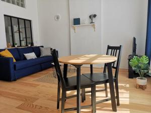 uma mesa e cadeiras numa sala de estar com um sofá azul em Appartement calme proche de la mer em Dunkerque