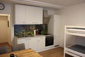 a kitchen with white cabinets and a sink and a table at Gemütliches 4er Apartment in Skilift-Nähe in Zell am See