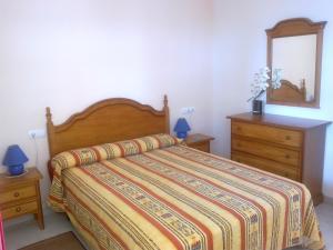 sypialnia z łóżkiem, komodą i lustrem w obiekcie Apartamento Amatista Calpe w mieście Calpe